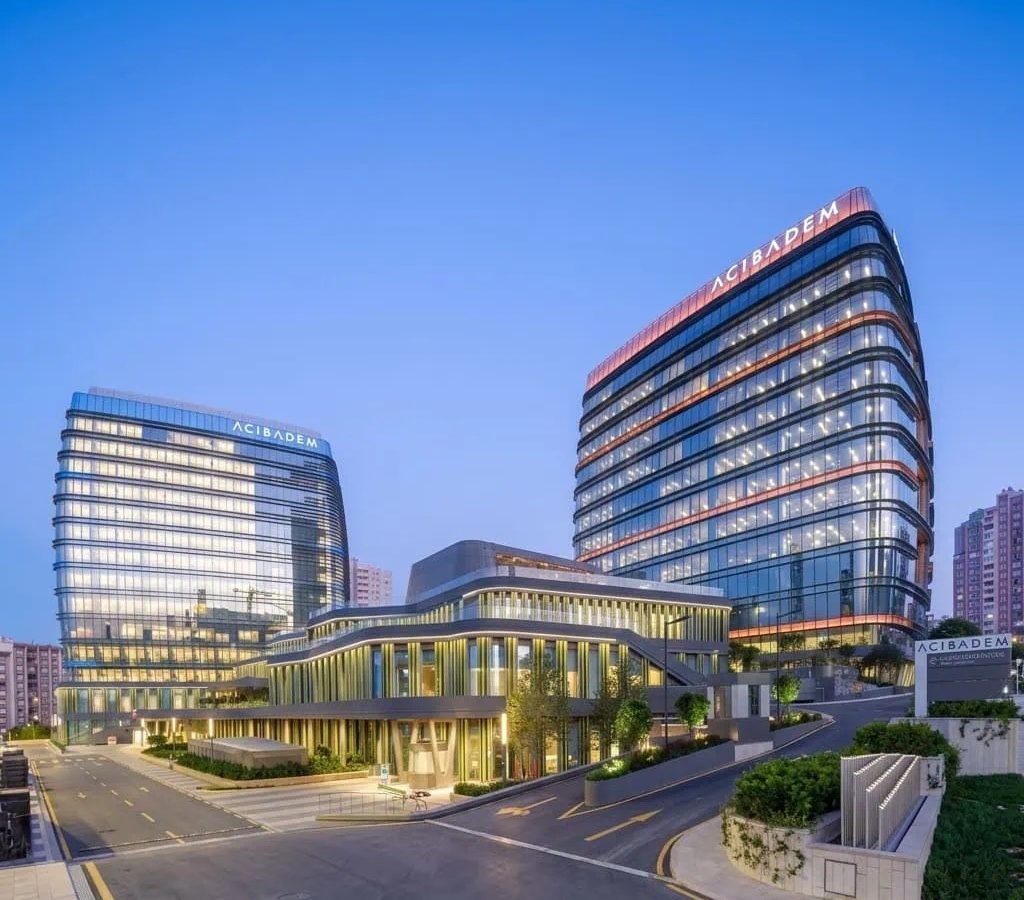 Modern Acibadem Atasehir Hospital building with glass facade at dusk.