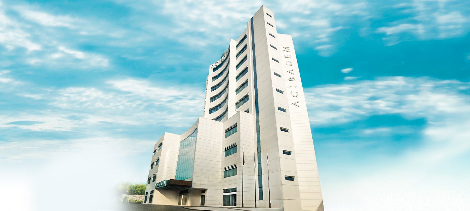 Acibadem Fulya Hospital modern high-rise building with blue sky background.